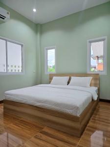 a large bed in a bedroom with two windows at Tasowa House in Chiang Rai