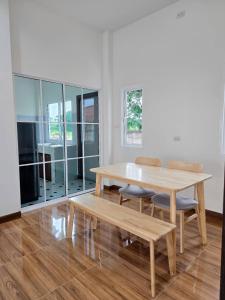 a dining room with a wooden table and benches at Tasowa House in Chiang Rai