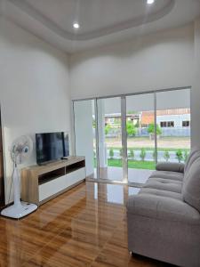 a living room with a couch and a flat screen tv at Tasowa House in Chiang Rai