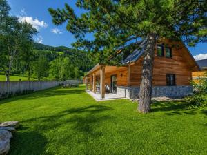 a log home with a tree in the yard at Alpenchalet am See in Afritz