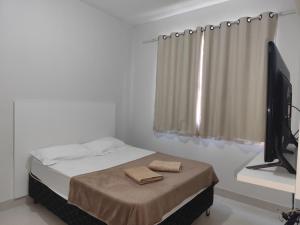 a bedroom with a bed and a flat screen tv at apartment work centro in Ubá