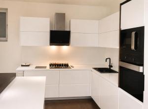 a white kitchen with white cabinets and a black refrigerator at NOVA residence in Sarajevo +4 photos
