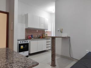 a kitchen with white cabinets and a sink and a stove at apartment work centro in Ubá