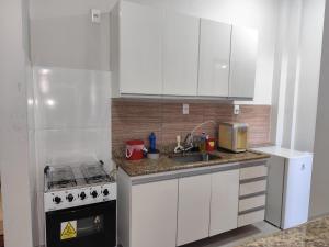 a white kitchen with a sink and a stove at apartment work centro in Ubá +25 photos