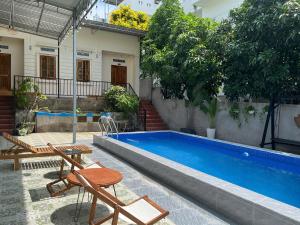 a swimming pool with a table and chairs next to a house at VitaSea Mui Ne homestay & pool in Mui Ne