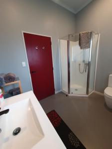 a bathroom with a white sink and a red door at The Red Shed in Matamata +63 photos