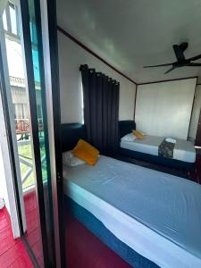 two twin beds in a room with a window at BIHING ANGAN water chalets in Semporna +9 photos