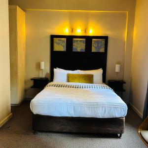a bedroom with a large bed with white sheets and yellow pillows at Native Suites 411 in Johannesburg