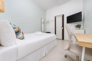 a white bedroom with a bed and a desk at Room 14: Chill City Veranda Near Miramar in San Juan