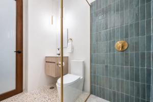 a bathroom with a toilet and a green tiled wall at Room 14: Chill City Veranda Near Miramar in San Juan