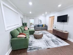 a living room with a green couch and a tv at Glam Parkville Experience! in Parkville