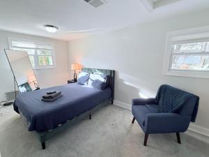a bedroom with a bed and a blue chair at Glam Parkville Experience! in Parkville