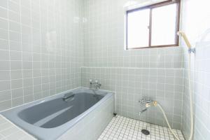 a bath tub in a bathroom with a window at Saka no Kaze in Onomichi