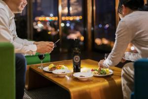 a table with two plates of food and a bottle of wine at Saka no Kaze in Onomichi