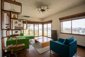 a living room with green chairs and a television at Saka no Kaze in Onomichi