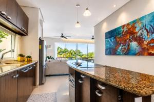 a kitchen with a large counter and a large painting on the wall at Sunset Condo 104 Puerta al Mar Isla Mujeres Mexico in Isla Mujeres