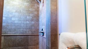 a shower with a glass door with a stone wall at Park Place by AvantStay in Paso Robles