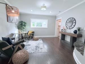 a living room with a table and a clock on the wall at Glam Parkville Experience! in Parkville