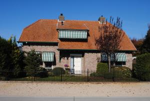 哈蒙特B&B Elegance Hamont的一座红色屋顶和黑色围栏的房子