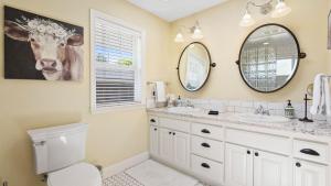 a bathroom with two sinks and a cow painting on the wall at 13th Street Retreat by AvantStay in Paso Robles +22 photos