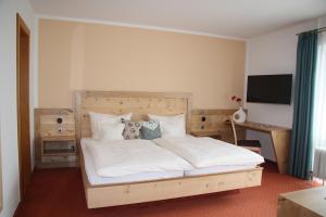 a bedroom with a large white bed and a desk at Landhaus Seehof in Füssen