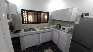 a kitchen with white cabinets and a sink and a microwave at Tam-Toboyah in Conakry