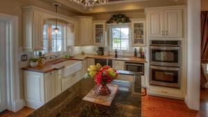a kitchen with white cabinets and a vase of fruit on a counter at Bliss House by AvantStay in Paso Robles +20 photos