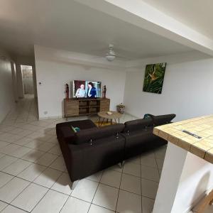 a living room with a black couch and a tv at Villa Floru in Le Carbet