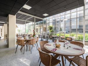 a restaurant with tables and chairs and windows at Ibis Styles Lyon Gorge de Loup Saphir in Lyon