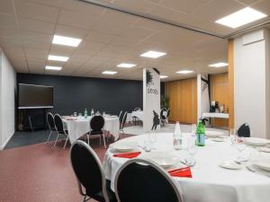 a conference room with white tables and chairs and a screen at Ibis Styles Lyon Gorge de Loup Saphir in Lyon