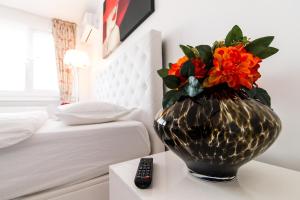 un vase avec des fleurs sur une table à côté d'un lit dans l'établissement Belvedere Danubius, à Galaţi