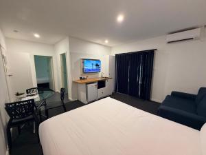 a bedroom with a bed and a table and a couch at The Esplanade Motel in Warners Bay