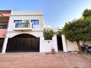 a white house with a black gate and a tree at Abbe Residence in Bamako