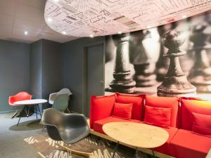 a room with a red couch and a table at ibis Avignon Sud in Avignon