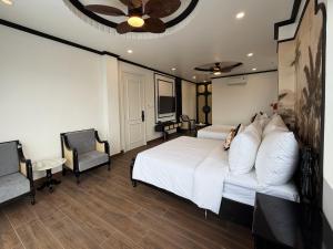 a bedroom with a white bed and two chairs at Celine Privé - Dalat Hotel in Da Thien +10 photos