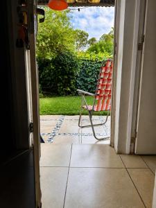a red chair sitting on the porch of a house at Casa cálida y confortable en Allen in Allen