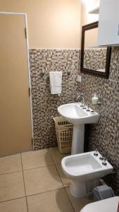 a bathroom with a sink and a toilet and a mirror at Casa cálida y confortable en Allen in Allen