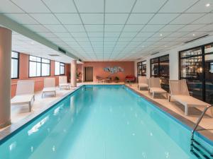 a pool in a hotel with chairs and a table at Hotel Mercure Blois Centre in Blois