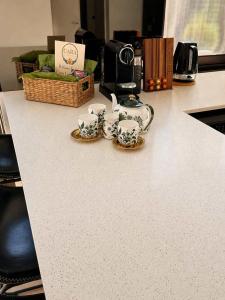 a counter with three tea cups and a basket on it at Cara Luxe Stays at Regents Park near Olympic Park and DFO in Regents Park