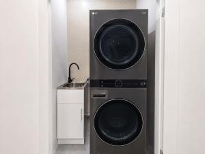 two washing machines in a kitchen with a sink at Cara Luxe Stays at Regents Park near Olympic Park and DFO in Regents Park +1 photo