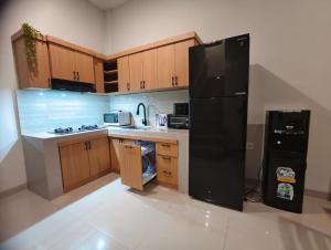 a kitchen with a black refrigerator and wooden cabinets at Sarining 2BR Villa With Pool in Uluwatu