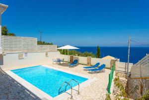 a swimming pool with chairs and an umbrella and the ocean at Villa Martha in Ieromónachos