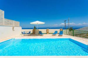 a swimming pool with chairs and an umbrella at Villa Martha in Ieromónachos