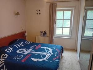 a bedroom with a bed with a blue comforter and a window at Kamer in Fermette Vlaamse Ardennen in Maarkedal