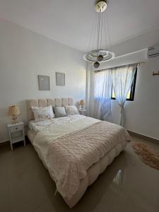 a white bedroom with a large bed and a chandelier at Villa Luminosa in Punta Cana +33 photos