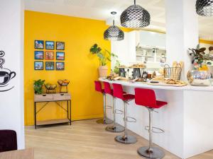 a kitchen with yellow walls and red bar stools at Mercure Nice Centre Grimaldi in Nice