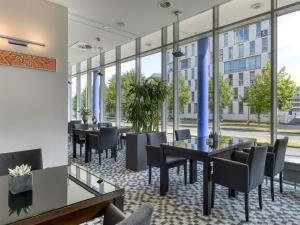 a restaurant with tables and chairs and large windows at Novotel Köln City in Cologne