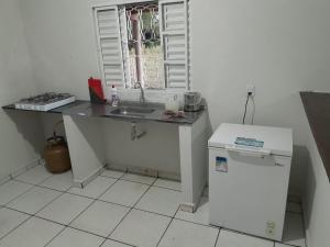 a kitchen with a counter and a sink and a refrigerator at Rancho do Véio in Aquidauana +4 photos