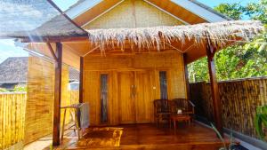 a small house with a straw roof on a deck at Dom Dom Guest House Gili Gede in Gili Gede