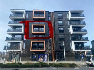 a tall apartment building with a red building at Central City Views In Heart of Central Chch by Stadium in Christchurch